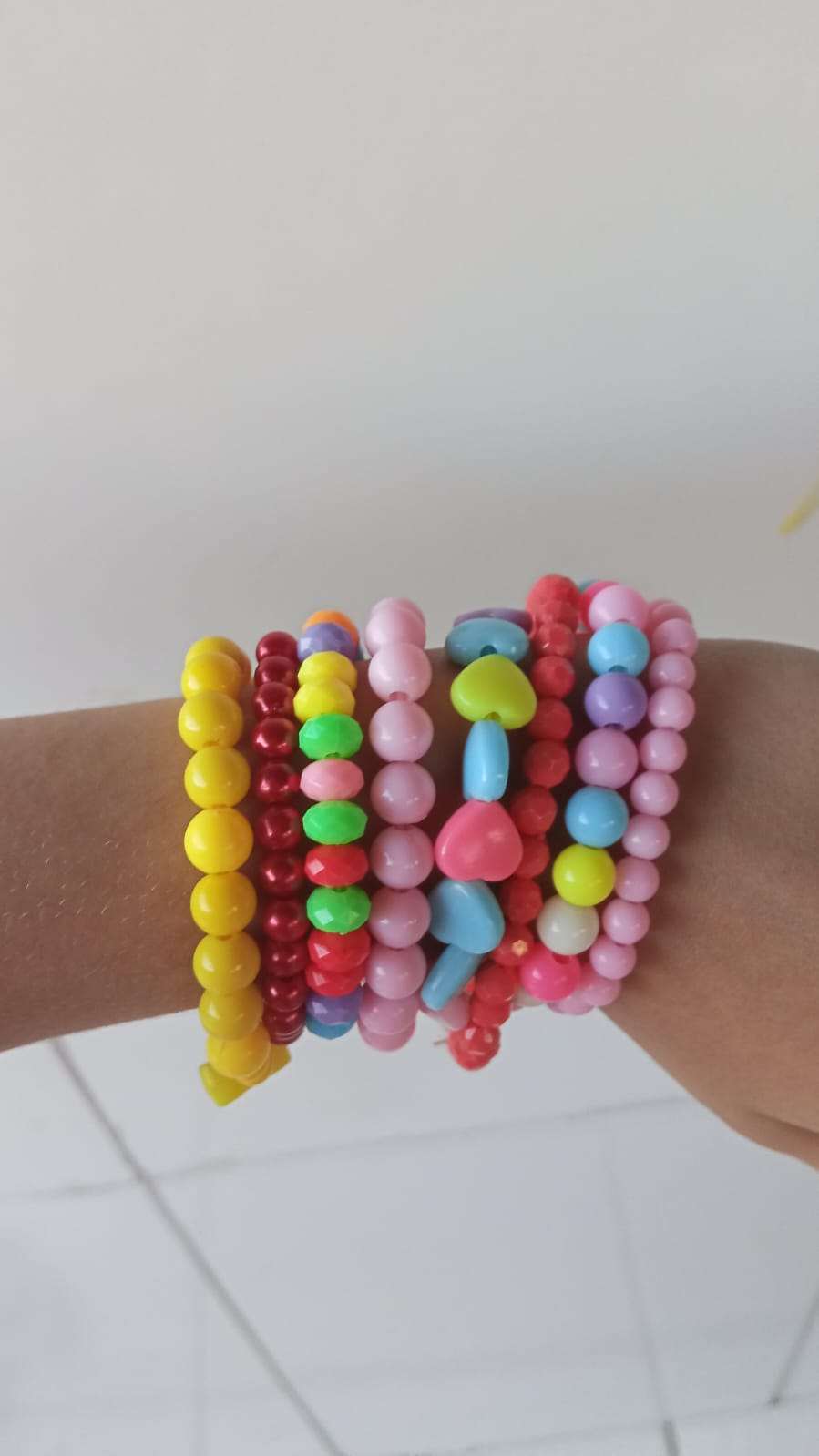 Várias pulseiras de bolinhas coloridas no pulso